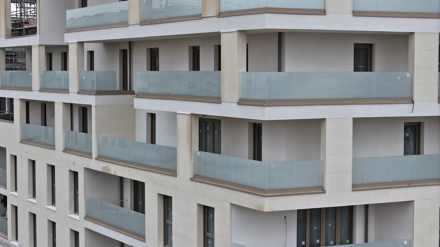 Détail de façade en pierre claire avec garde-corps vitrés, pris en drone